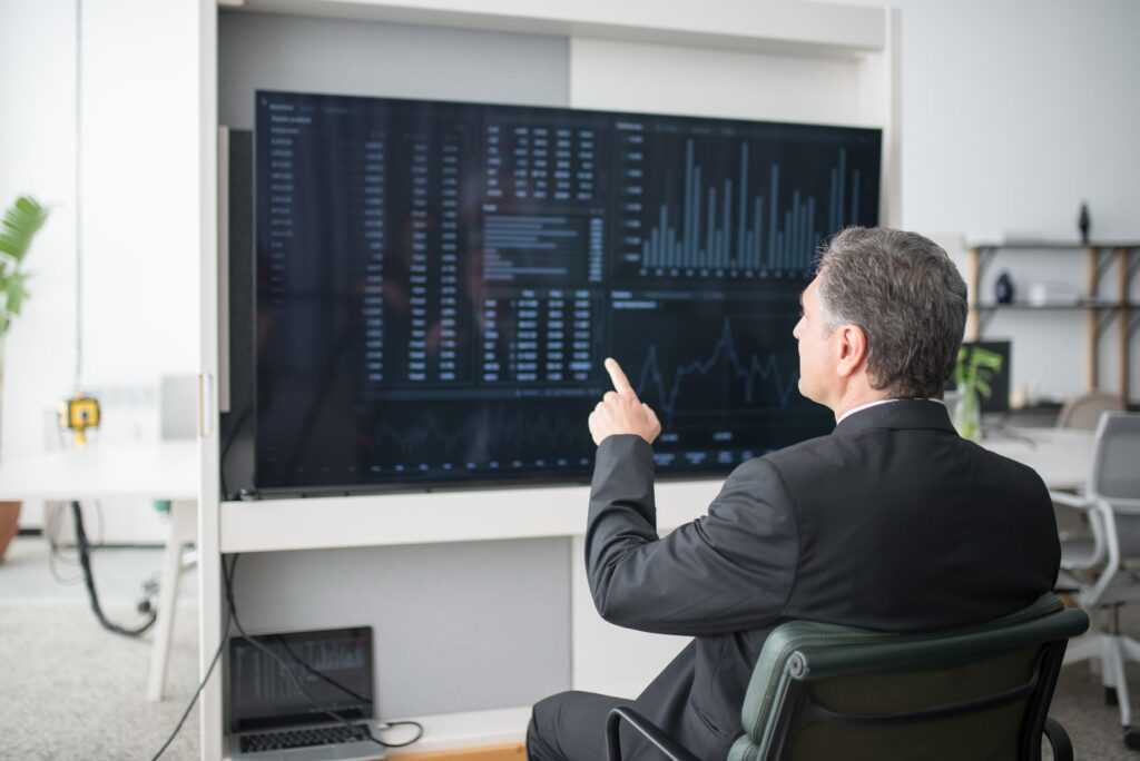 Gerente analizando un dashboard de tecnología en una pantalla grande durante una consultoría IT