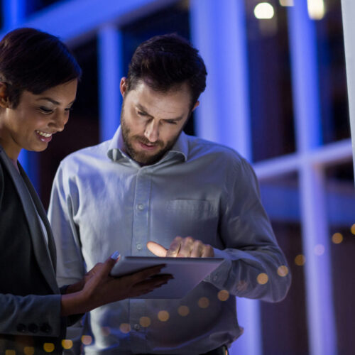 Businesspeople using digital tablet in office at night